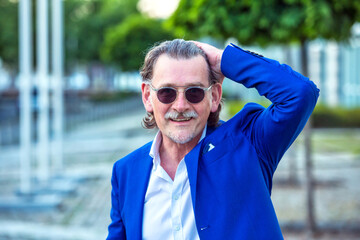 handsome businessman in his 50s with sunglasses standing outside