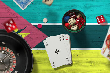Mozambique casino theme. Aces in poker game, cards and chips on red table with national flag...