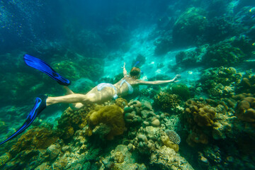Naklejka na ściany i meble Woman snorkeling in white bikini swimming deep in coral reef of Surin Islands, Andaman Sea, North of Phuket, Phang Nga in Thailand. Ko Surin Marine National Park, underwater scene. Watersport activity