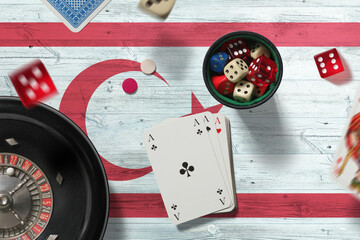 Northern Cyprus casino theme. Aces in poker game, cards and chips on red table with national flag background. Gambling and betting.