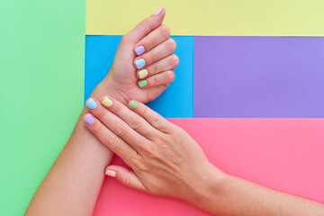 Female hands with bright summer nails on a colorful background. Top view