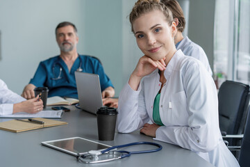 Young female doctor sitting and looking at camera during the meeting in hospital
