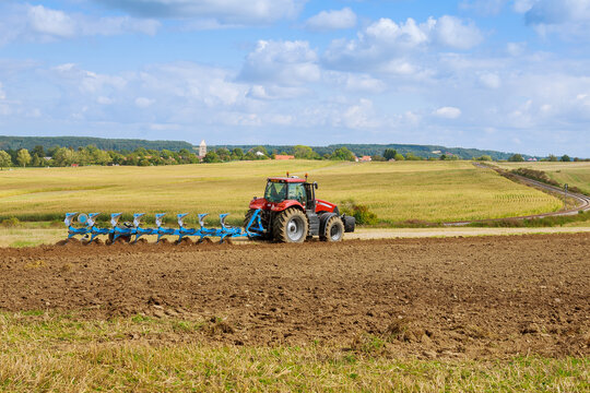 A tractor with a large plow plows a field. Tractor with agricultural attachment.