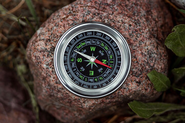 Magnetic compass with a black dial on a stone top view. The concept of travel, finding a path,...