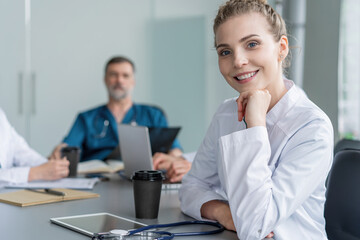 Young female doctor sitting and looking at camera during the meeting in hospital