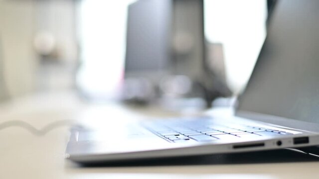 Close-up of a call center operator's desktop. Faceless business woman taking headset from laptop keyboard. The beginning of the working day of an office employee.