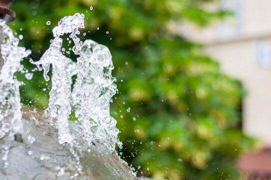 Water gurgling from a street fountain. A splash of water in a fountain, an abstract image. © Maks_Lab