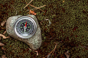 Magnetic compass with a black dial on a stone top view. The concept of travel, finding a path,...