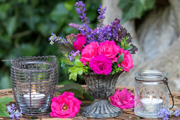 Dekoration mit Sommer-Blumenstrauß in Pink und Lila und Windlichtern