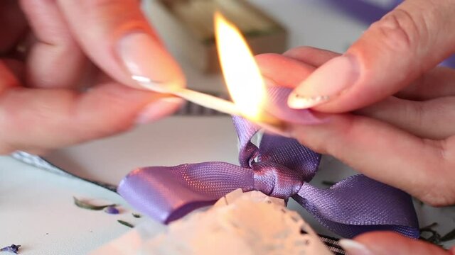 A woman cauterizes a match with a ribbon tied to a bow. Bouquet tied with a ribbon. Close-up shot.