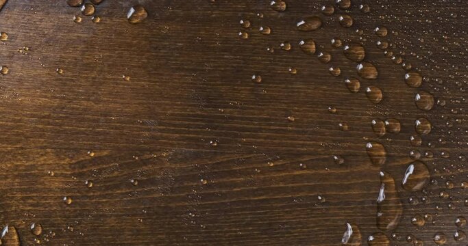 Raindrops on a wooden board. The wind blows off drops of water.