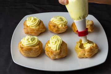 Filling puff pastries with vanilla creme.