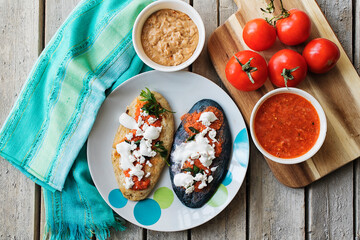 Prepared mexican traditional tlacoyos with red sauce and tomatoes on a wooden table
