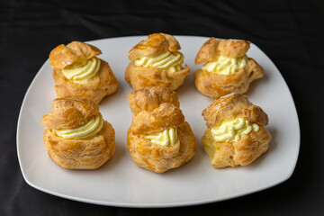 Vanilla creme custard pastries are displayed on a white dish with a black background.