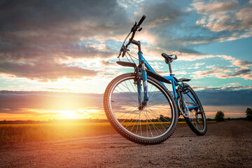 Fototapeta na wymiar Bike on a sunset background. The concept of a healthy lifestyle, sports training, cardio load. Copy space.