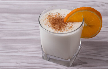 sweet milky desert or coconut milk and a slice of orange in a glass
