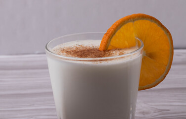 sweet milky desert or coconut milk and a slice of orange in a glass