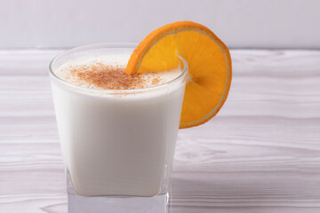sweet milky desert or coconut milk and a slice of orange in a glass