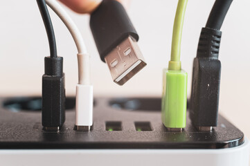 Modern convenient multi-port usb charger for devices. Close-up of inserted multi-colored cables in...