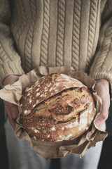 Baked bread of sourdough in hands. Artisan bread. The bread of sourdough, homemade and natural creation. The sourdough has natural yeast, which makes the food healthier, as well as rich.