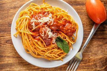 spaghetti dinner with meatballs and tomato sauce  arranged in a wooden background.