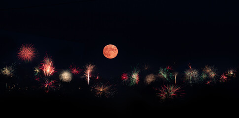 Fireworks set off on the hillside as the full moon rises on the forth of July