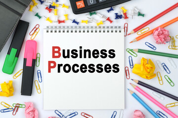 On the table is a calculator, diary, markers, pencils and a notebook with the inscription - Business Processes