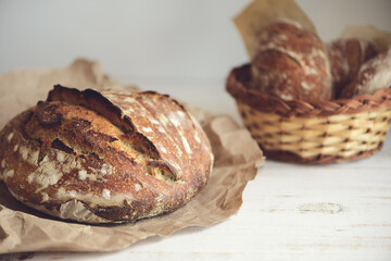 Baked bread of sourdough in hands. Artisan bread on light background. The bread of sourdough, homemade and natural creation. The sourdough has natural yeast, which makes the food healthier, as well as
