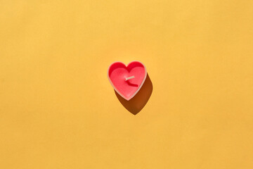 Fototapeta premium heart-shaped candle on a yellow background. isolate. place for the label