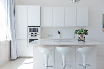 Cozy luxury modern interior design of a studio apartment in extra white colors with fashionable expensive furniture in a minimalist style. white tiled floor, kitchen, relaxation area and workplace