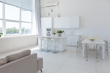 Cozy luxury modern interior design of a studio apartment in extra white colors with fashionable expensive furniture in a minimalist style. white tiled floor, kitchen, relaxation area and workplace