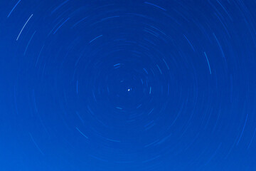 Background of round or circular star track or trajectory on the blue clear night sky. Symbol of...