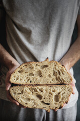 Baked bread of sourdough in hands. Artisan bread. The bread of sourdough, homemade and natural creation. The sourdough has natural yeast, which makes the food healthier, as well as rich.