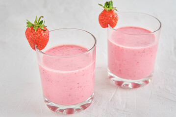 Two glasses with strawberry shake on white background