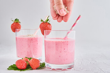 Strawberry milk shake in glass with straw and fresh berries on a white background