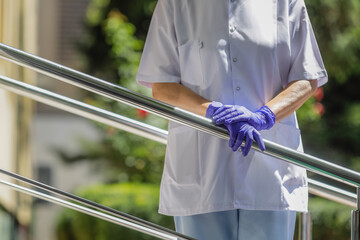 Details with the hands of a woman medic leaning patiently on a metal rail.