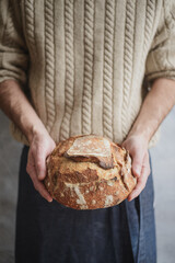 Obraz na płótnie Canvas Baked bread of sourdough in hands. Artisan bread. The bread of sourdough, homemade and natural creation. The sourdough has natural yeast, which makes the food healthier, as well as rich.