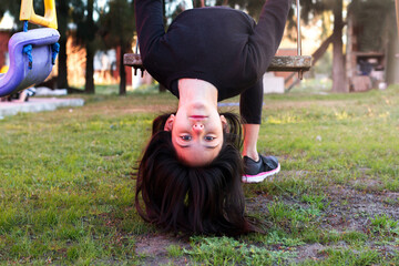 portrait of little girl with head upside down in swing