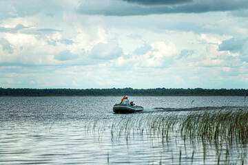Father and son ride a motor boat on the lake. The concept of family, summer vacation, generation. Copy space.