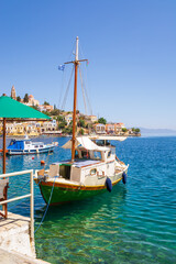 Boat anchoring in beautiful Symi bay with emerald green sea water. Symi island, Greece.