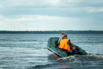 Fototapeta premium Father and son ride a motor boat on the lake. The concept of family, summer vacation, generation. Copy space.