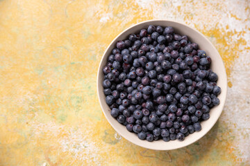 Forest berries blueberry,bramble in a ceramic bowl.Top view.Space for text.fresh picked blueberries on yellow painting background.Blueberry antioxidant. Concept for healthy eating and nutrition