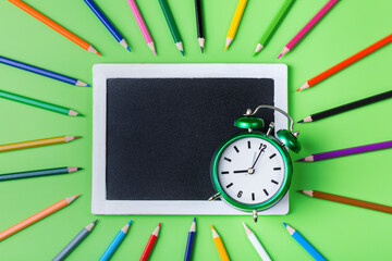 Colourful pencils, alarm clock chalkboard. Back to school concept