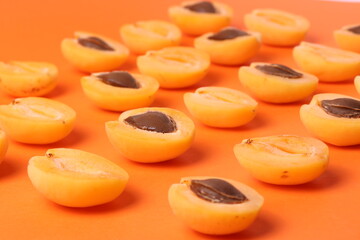 background pattern style shot of several orange ripen apricots with seeds on the bright orange color background