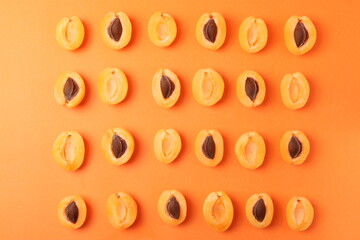 background pattern style shot of several orange ripen apricots with seeds on the bright orange color background