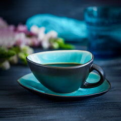 Black coffee and pink flowers on a black background, copy space