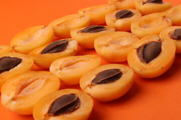background pattern style shot of several orange ripen apricots with seeds on the bright orange color background