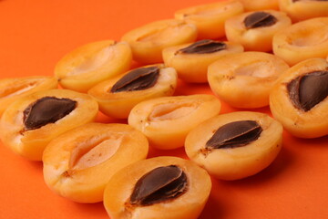 background pattern style shot of several orange ripen apricots with seeds on the bright orange color background