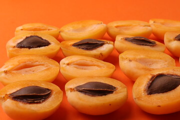 background pattern style shot of several orange ripen apricots with seeds on the bright orange color background