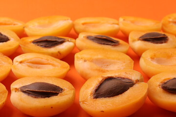 background pattern style shot of several orange ripen apricots with seeds on the bright orange color background